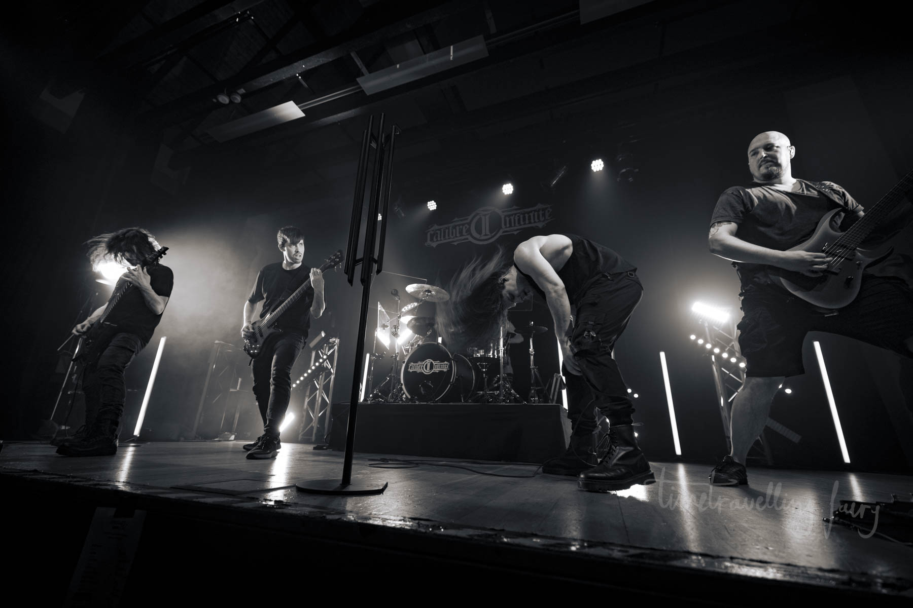 Calibre Infinite performing live in a dramatic black-and-white full-band stage shot