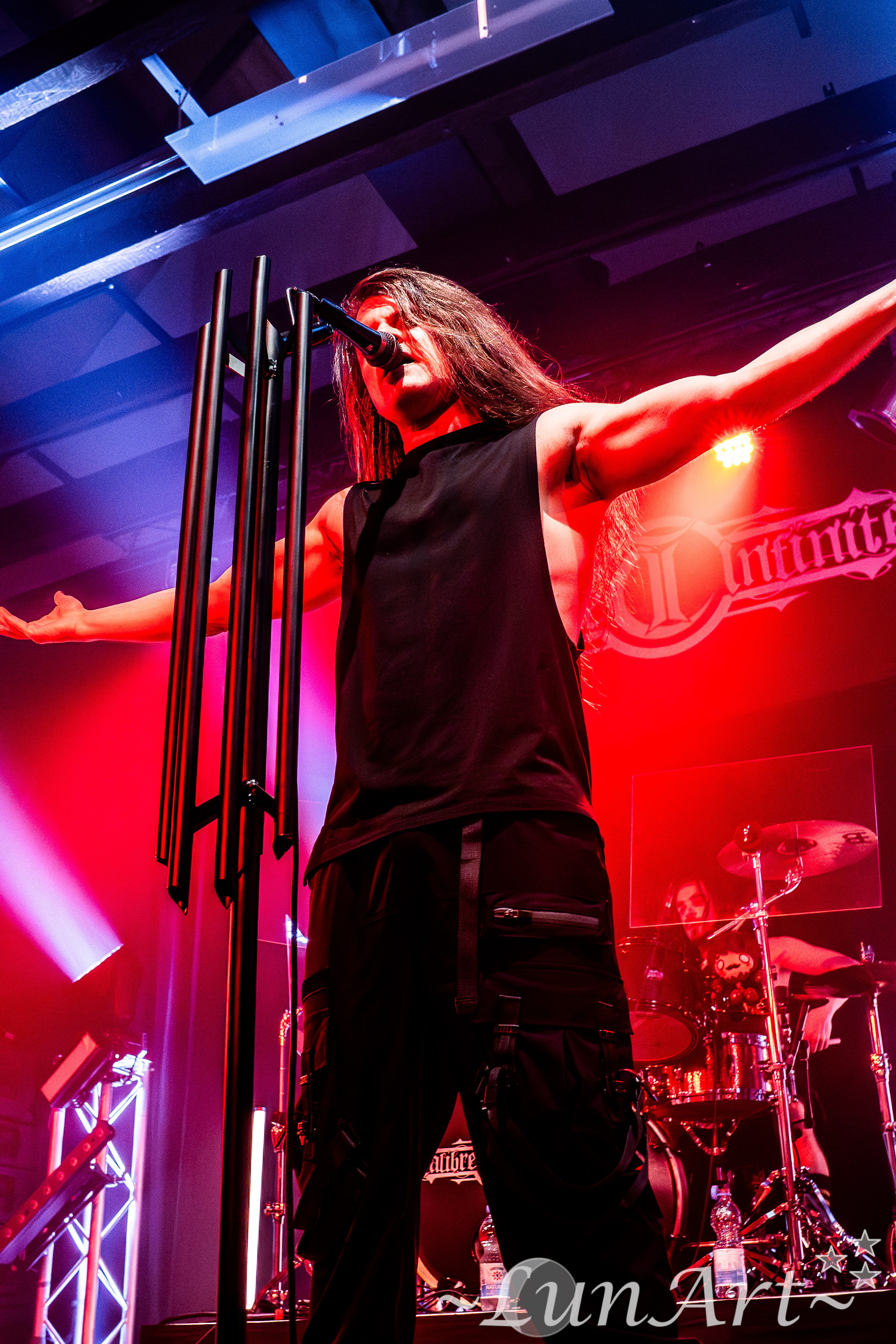 Peter on stage under red lighting with arms outstretched